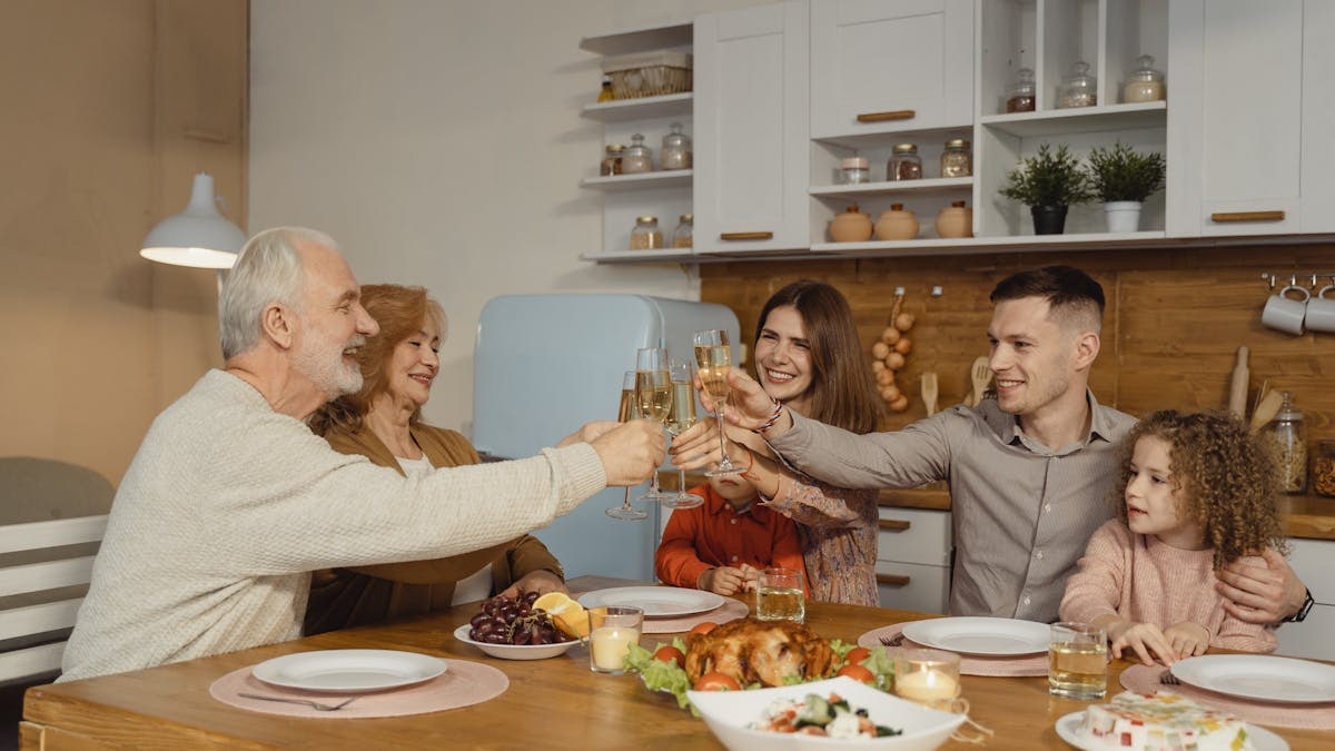 A joyful family toasting at a dinner table indoors, celebrating a special occasion.
